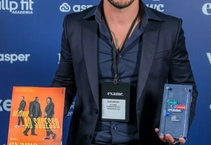 Alex Sales segurando o troféu da Exame e a edição da revista com a reportagem