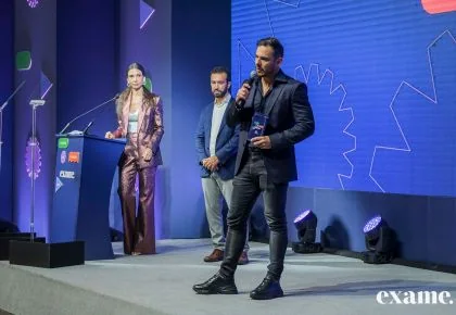 Alex Sales no palco da premiação da Exame, ao lado dos apresentadores