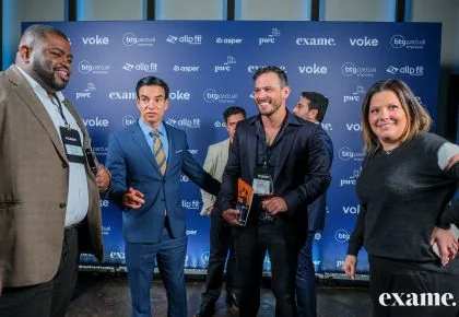 Alex Sales com o troféu, ao lado dos demais homenageados, diante do painel da premiação da Exame